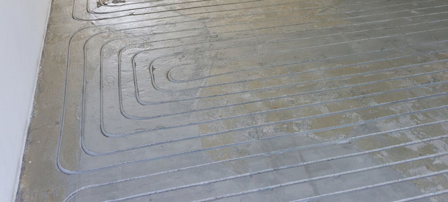 In einen Estrich eingefräste Heizungsrohre einer Fußbodenheizung in parallelen Schleifen.